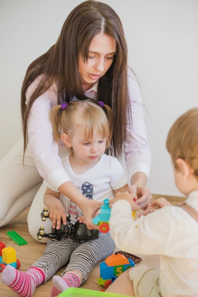 Deux enfants jouant sous la surveillance d'une educatrice